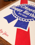 Birthday card with red and blue design on a wooden surface