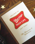 Card with 'Marriage High Life' design on a wooden surface with stars.