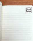 Open notebook with lined pages on a wooden surface, featuring the 'Flame Tree' brand.