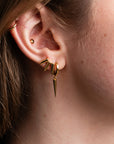 Close-up of a person wearing gold earrings with a blurred background