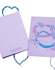Two purple notebooks with jewelry designs on a white background