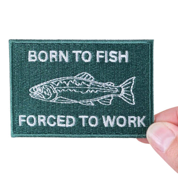Patch with text 'Born to Fish, Forced to Work' held by a hand on a white background