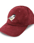 Red corduroy cap with a bird embroidered on a white background