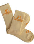 Beige socks with 'JET LAGGED' text on a white background