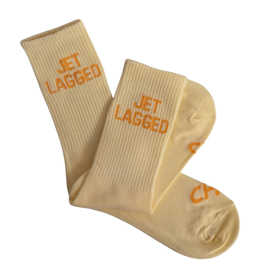 Beige socks with 'JET LAGGED' text on a white background