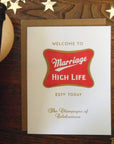 Card with 'Marriage High Life' design on a wooden surface with stars.