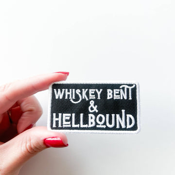 Patch with 'Whiskey Bent & Hellbound' text held by a hand on a white background